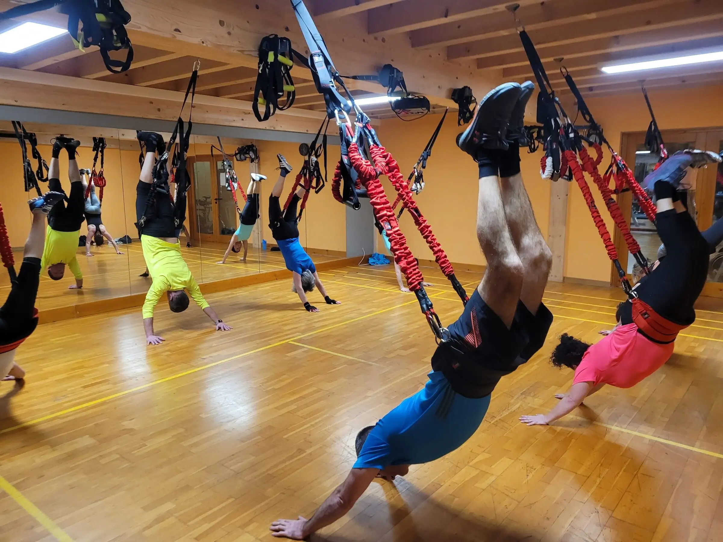 Kursgruppe im Handstand in den Bungee-Seilen des 4D PRO, vorn ein Teilnehmer kopfüber