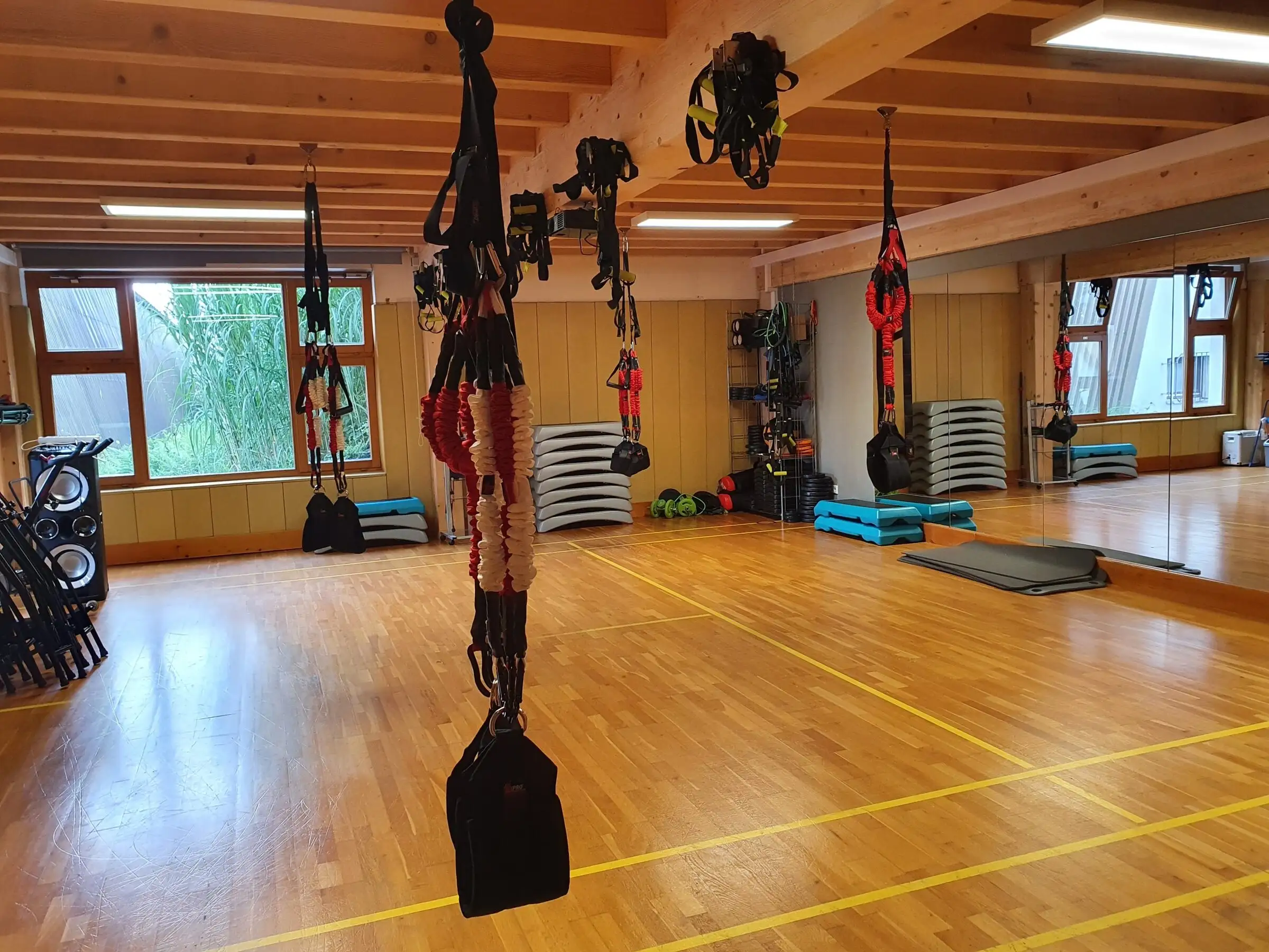 Leere Halle mit Holzboden, von der Decke hängen die Seile und Schlingen des 4D PRO