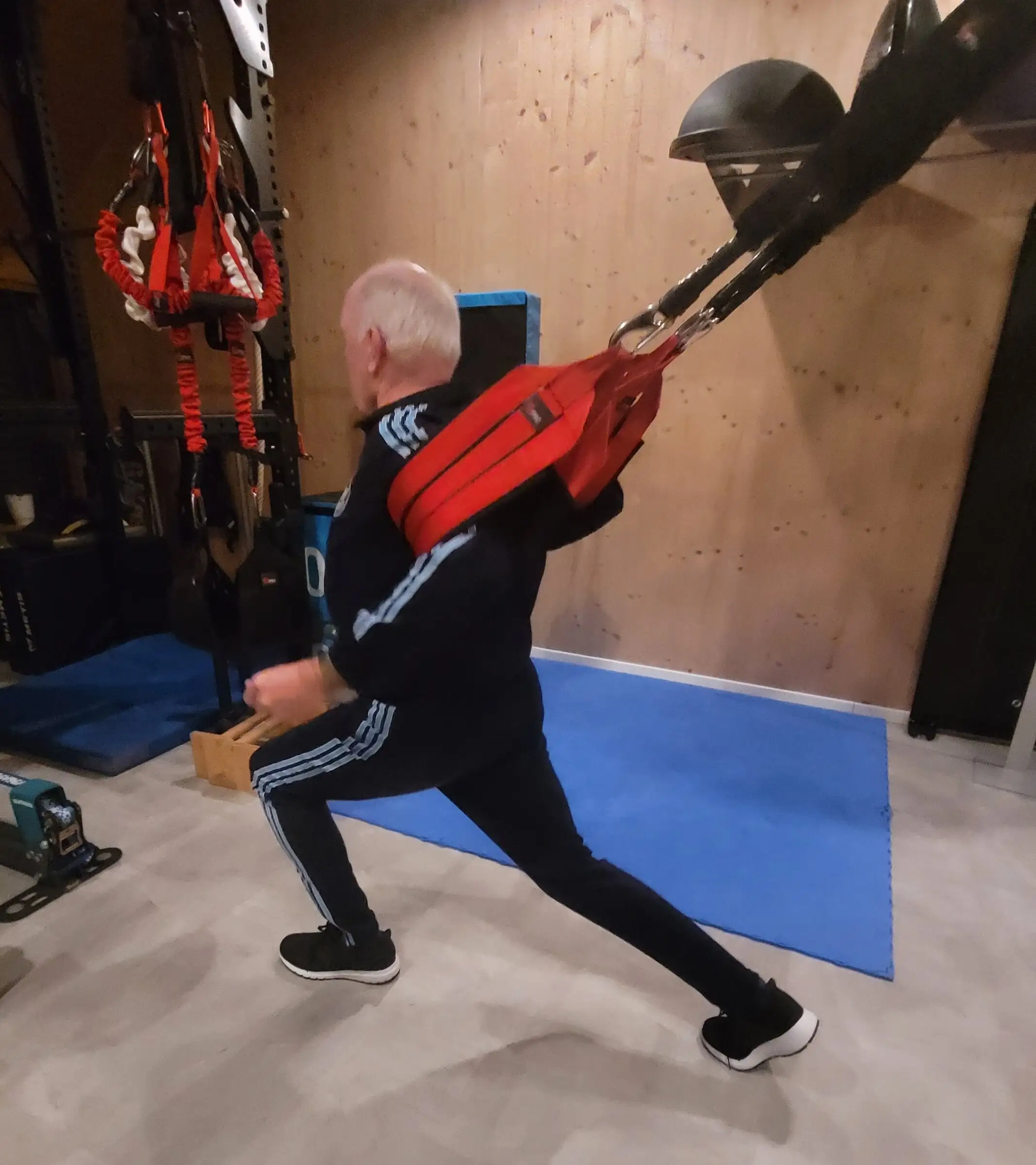 Älterer Kunde im Ausfallschritt im 4D PRO Schlingentrainer, das vordere Knie steht über dem Fuß