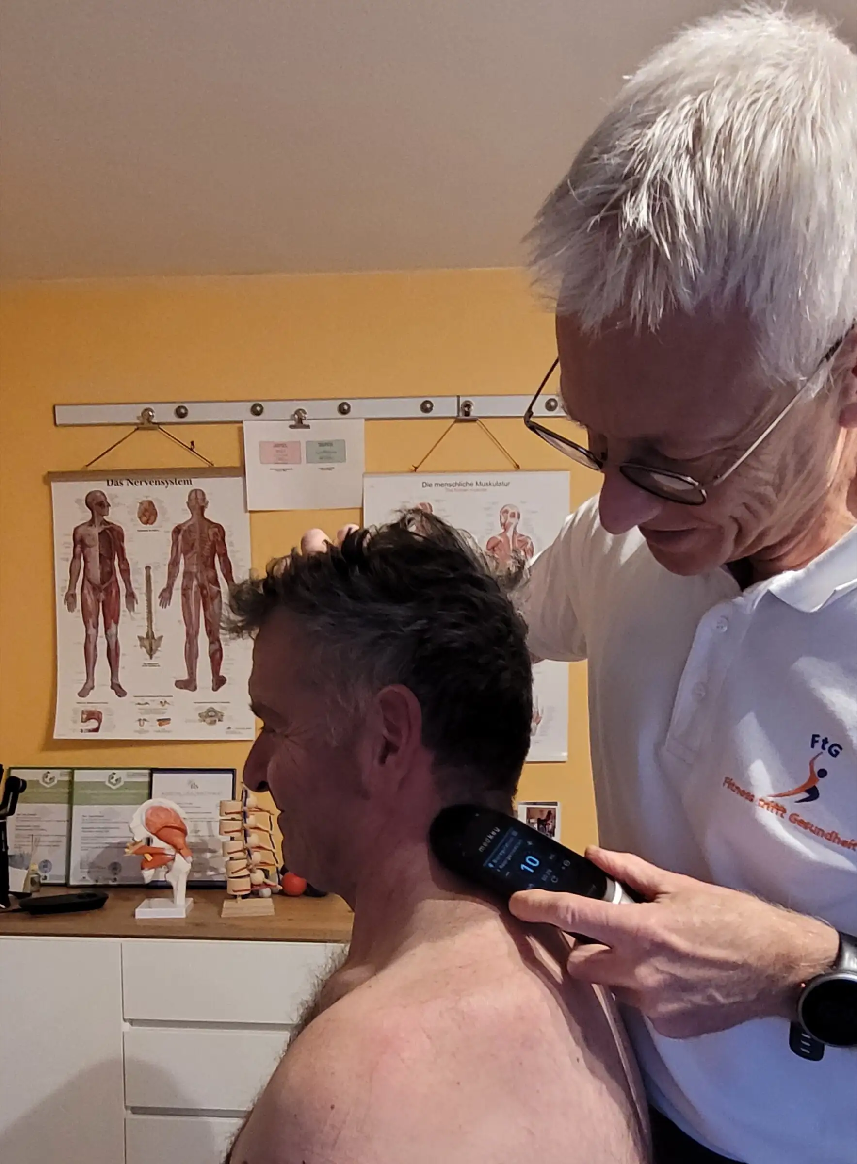 Uwe Schapeit setzt das MedKey-Handgerät am Nacken eines Kunden an