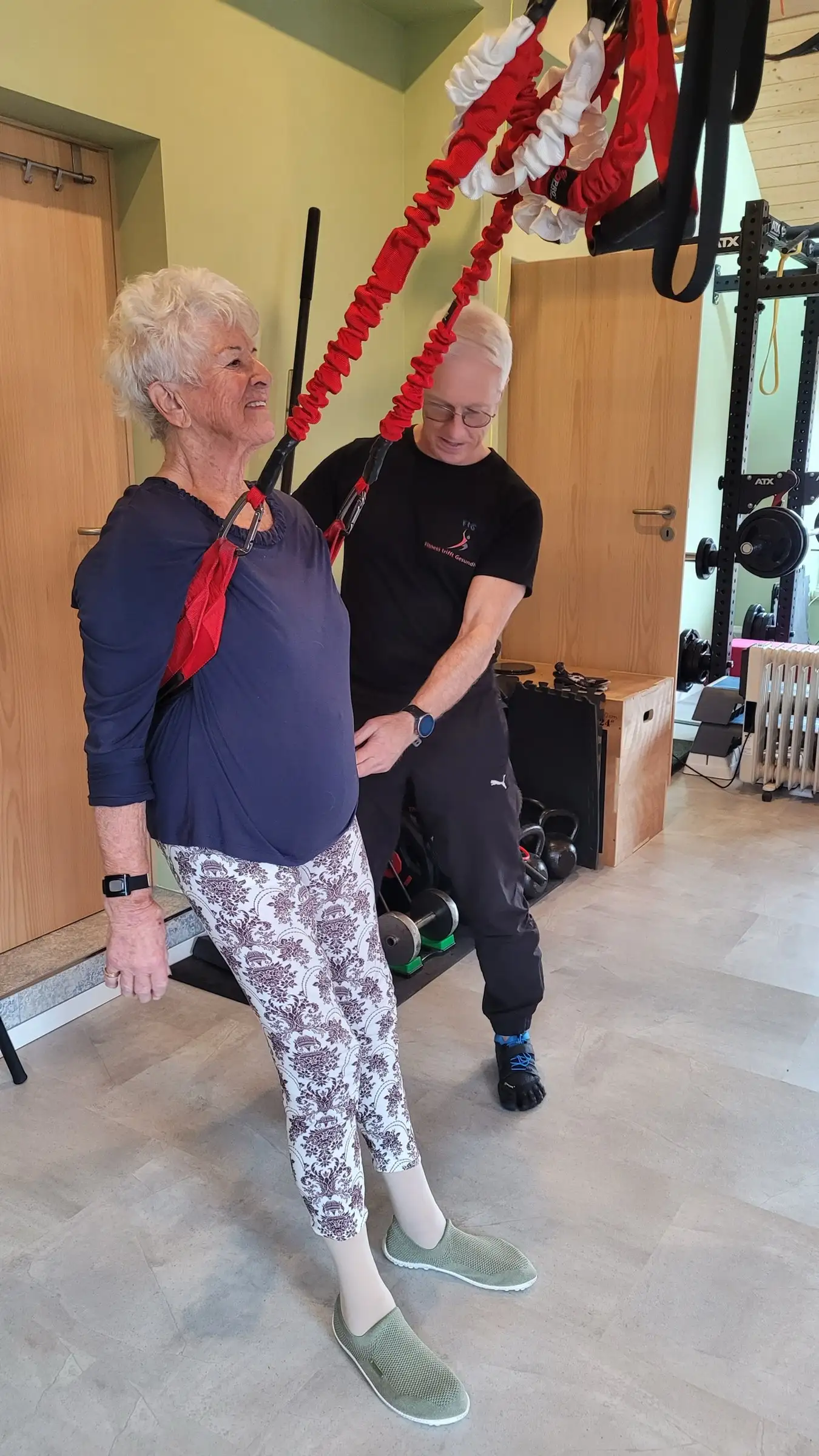 Seniorin steht in den Schlingen des 4D PRO, Uwe Schapeit steht hinter ihr